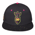 A black snapback baseball lifestyle cap with a flat brim, featuring a central embroidered graphic of a Nukes bomb with pink, yellow, and green details. The cap has pink snapback buttons and multicolor paint splatter details on the front panels and brim.