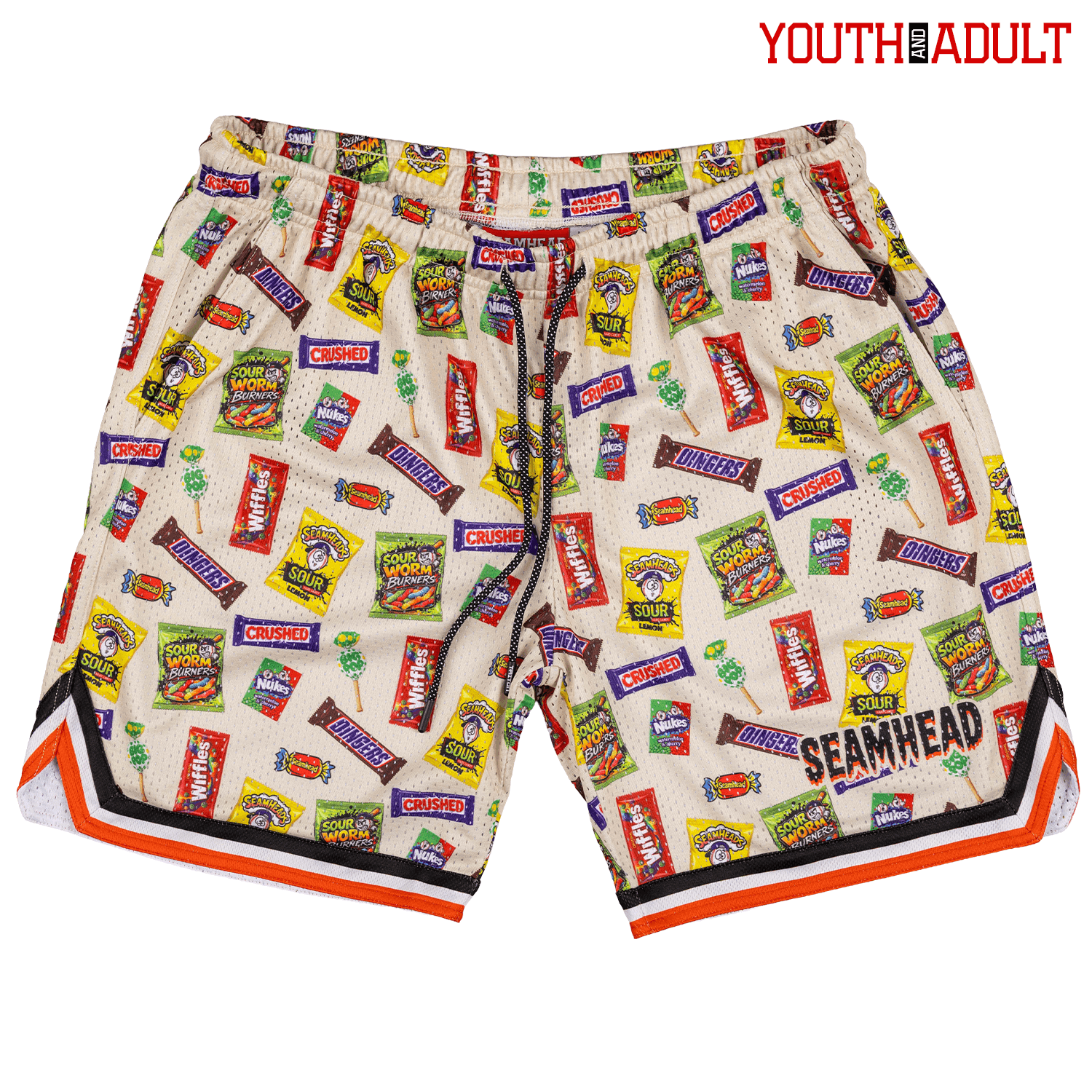 A pair of Halloween youth/adult lifestyle baseball 101 mesh shorts featuring an all-over print of various candy and snack packages on a cream mesh fabric, with orange, black, and white striped trim along the hem. The brand 'SEAMHEAD' is printed on the front.